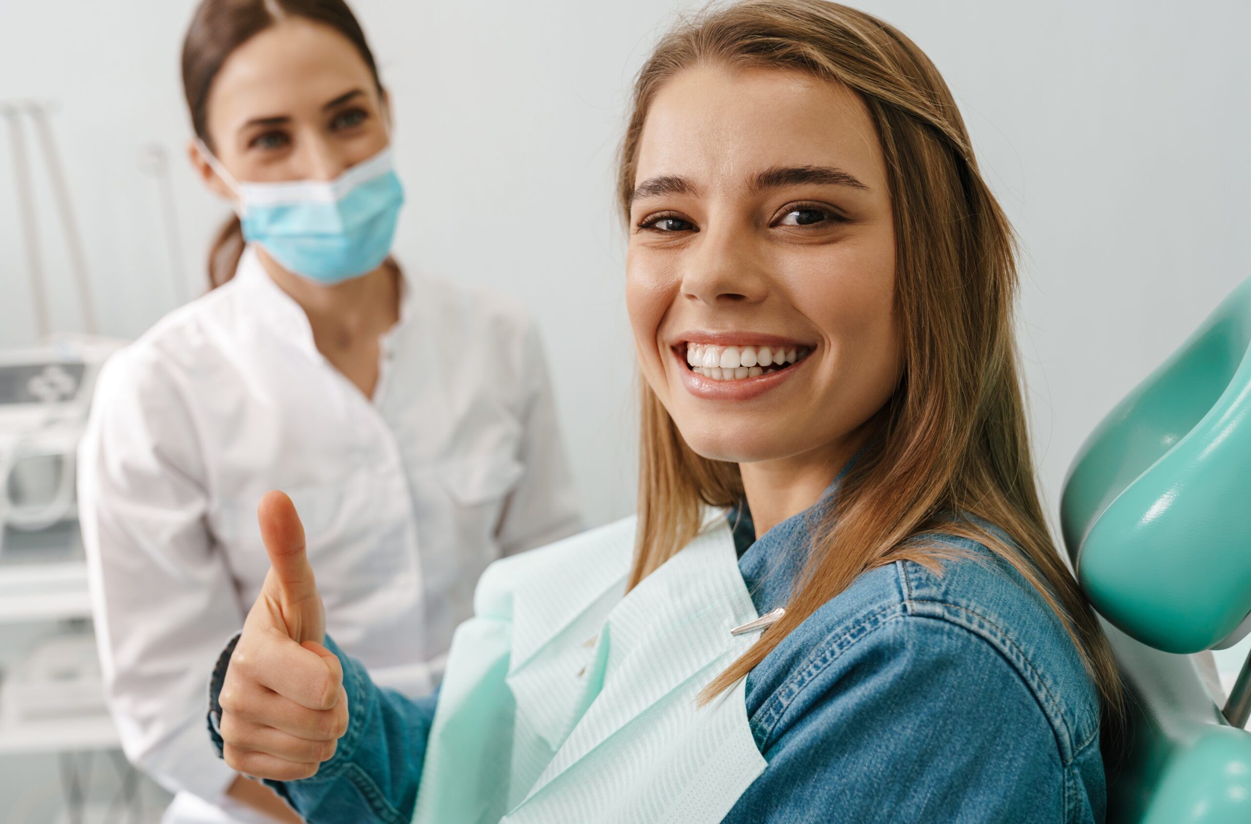 adult smiling in the dental chair with a thumbs up